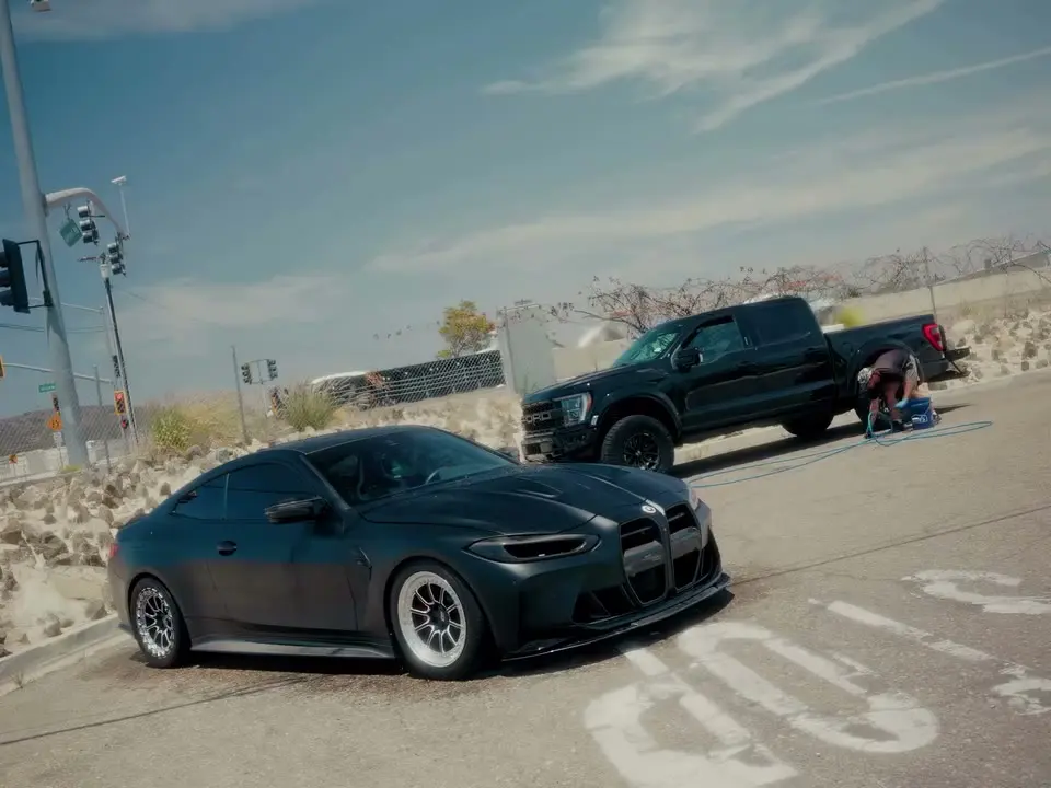BMW M car and a lifted truck being detailed on site